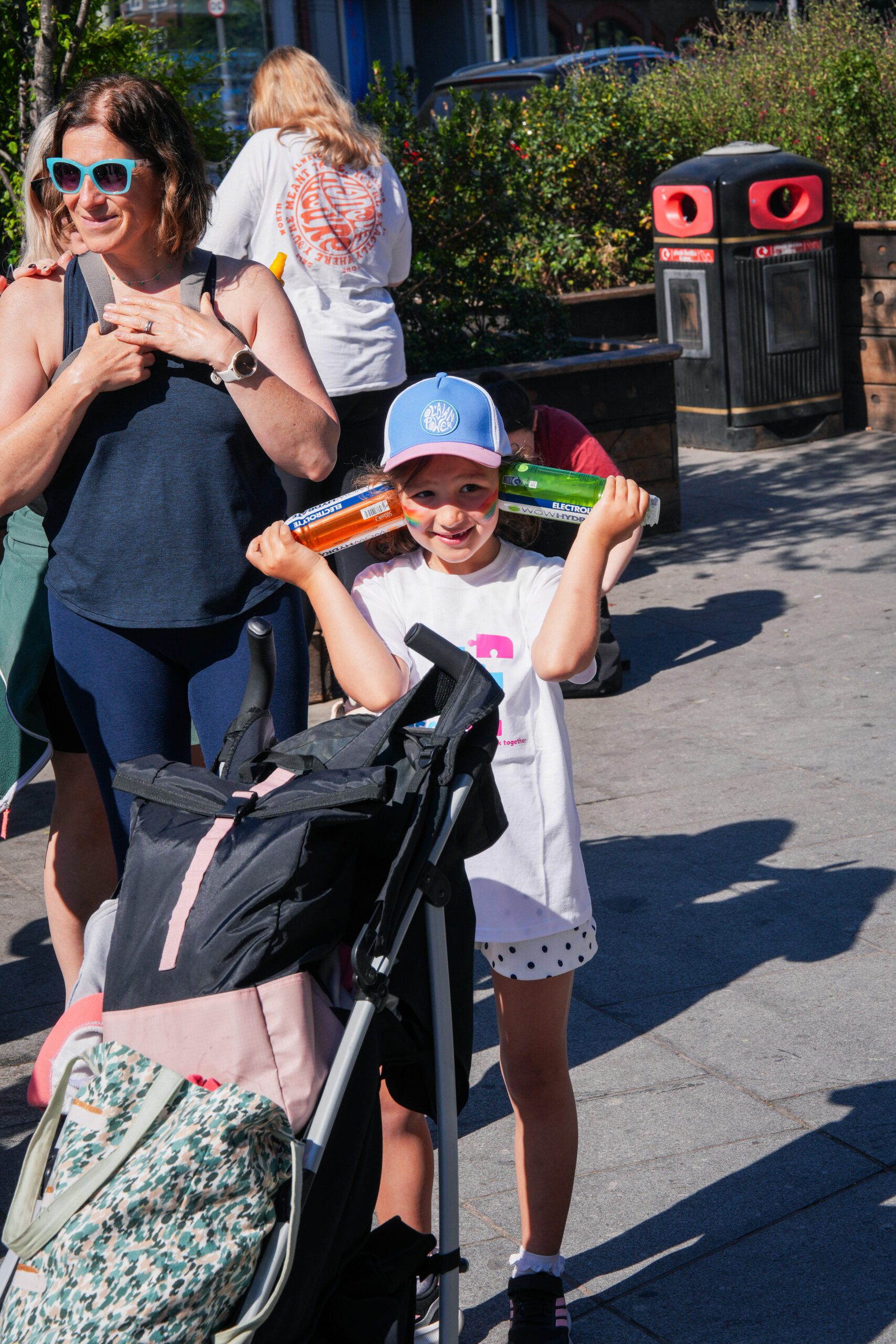 A girl standing next to a buggy wearing a Jigsaw4u tshirt ready for the walk, holding two WOW Hydrate water bottles, who sponsored the walk.