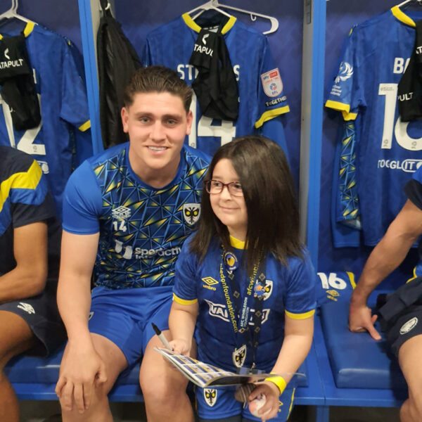 Jigsaw4u child mascot with AFC Wimbledon player in player changing room. Activites4u event with Jigsaw4u offered by Robert Holmes.